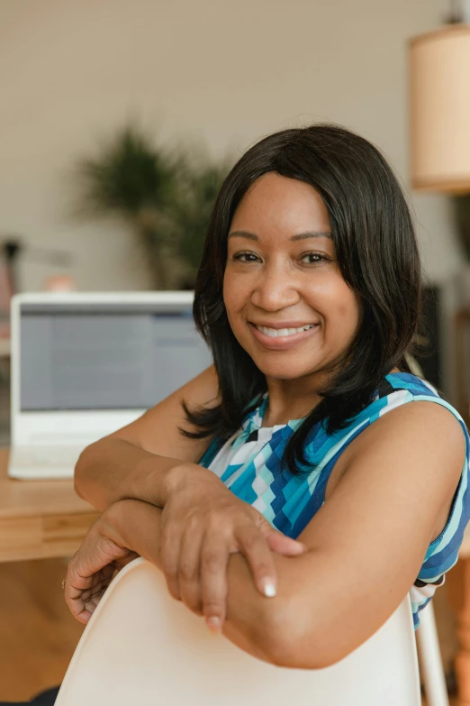 woman at a desk smiling to the camera with arms extended