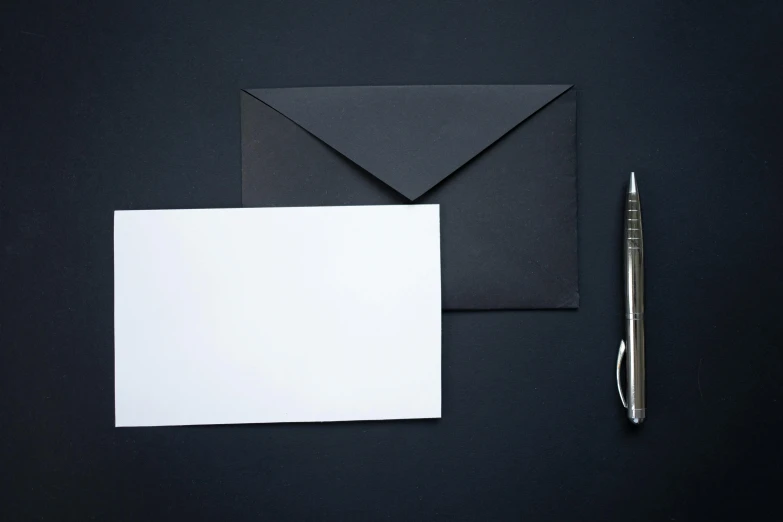 a pen sits next to some paper and two envelopes