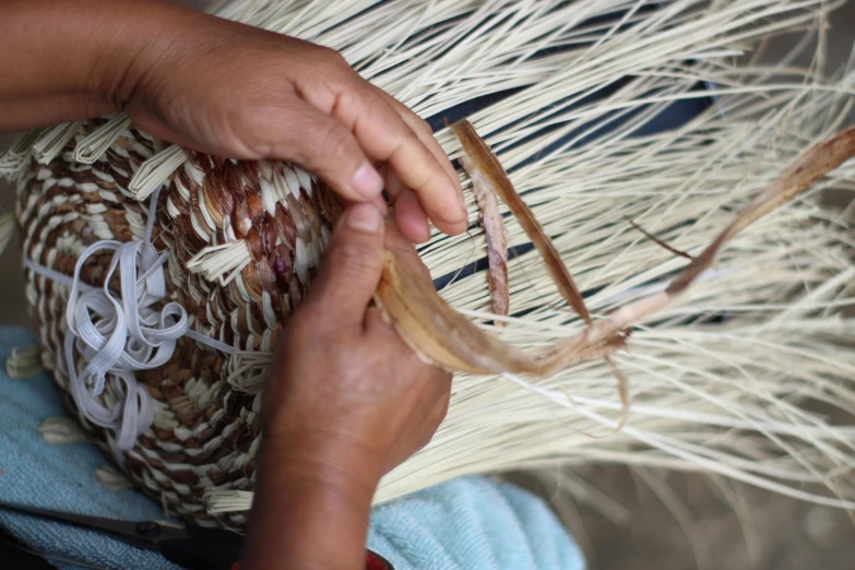 an weaving artist is weaving a loom of straw with her hands