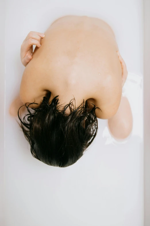 a man laying back in a bathtub with his hair on the ground