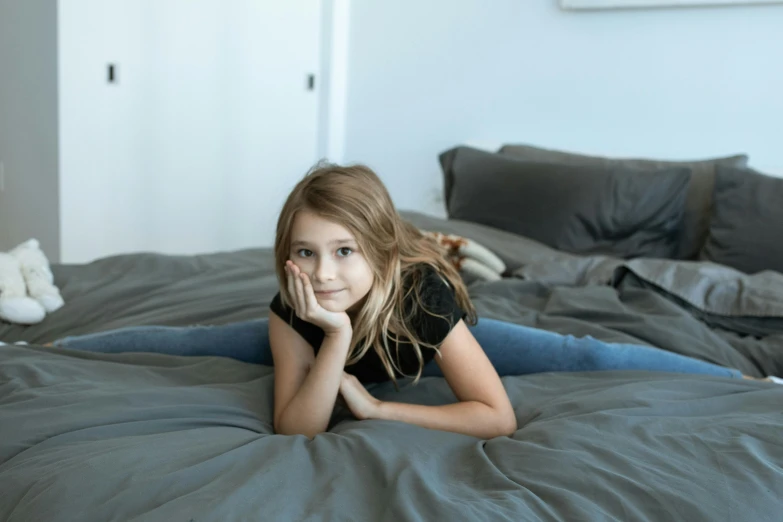 a little girl laying on a bed posing for a picture