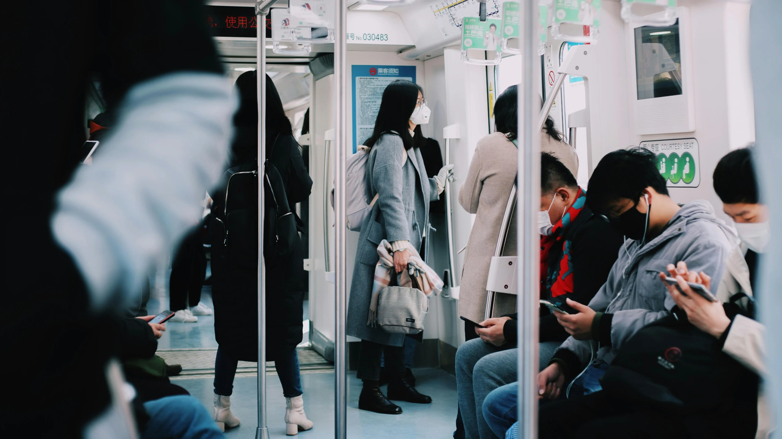 several people sitting in the subway on cellphones