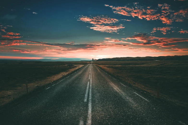 a sun going down on the road during a cloudy sky