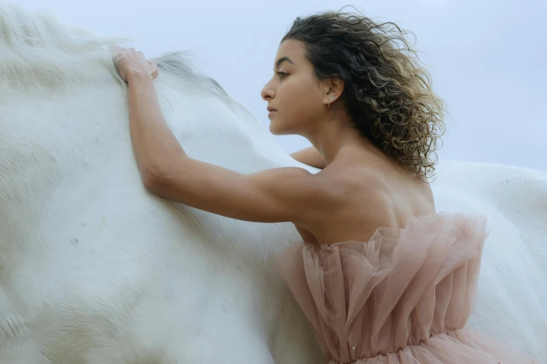 a woman is hugging a white horse in front of the ocean