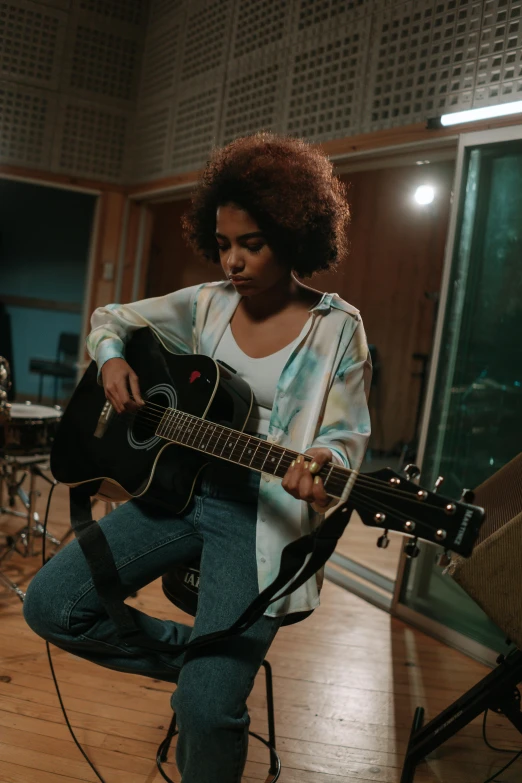 a woman holding a guitar while kneeling down