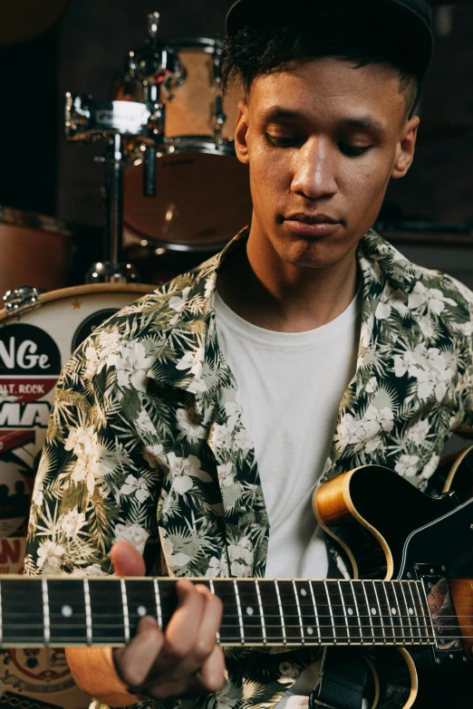 a young man playing an electric guitar with his eyes closed