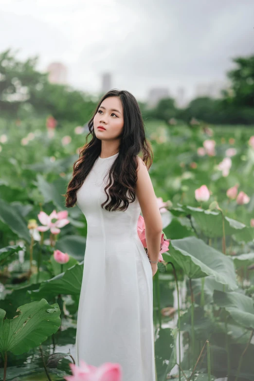 a woman stands in a field of flowers