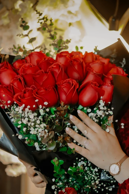 a woman is holding a bouquet of red roses