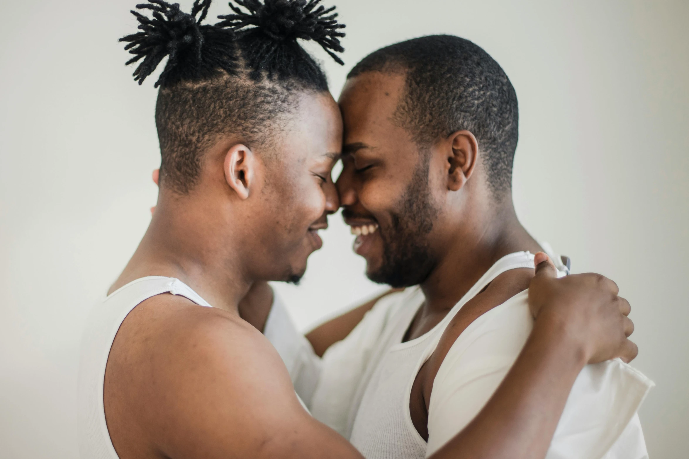 a black man with a mohawk gives a smiling woman a hug