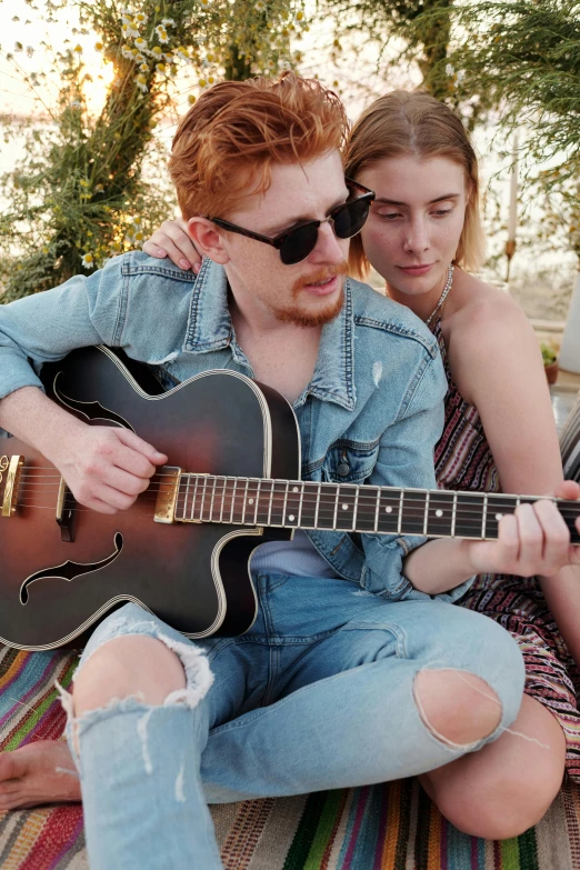 two people are sitting together and one has a guitar