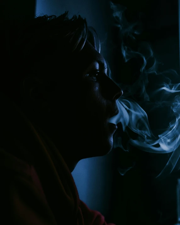 a man smoking a cigarette, in the dark