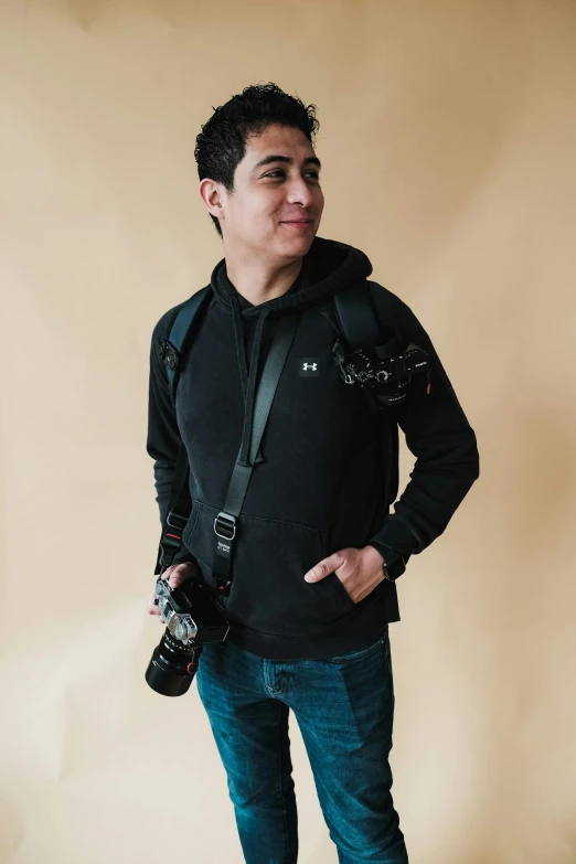 man wearing glasses holding camera in front of a beige background