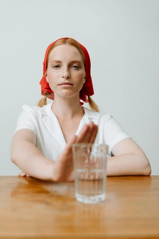 a girl is sitting at a table with a glass