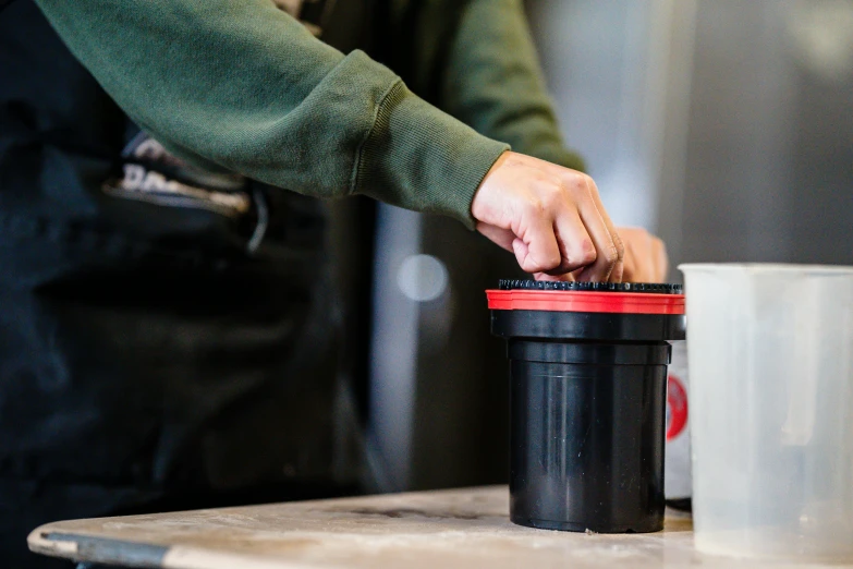 the man is sorting coffee cups into a trash can