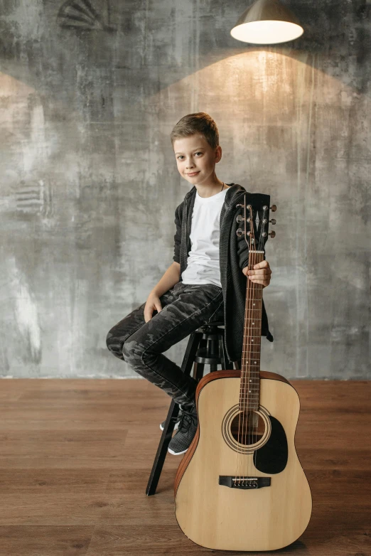  sitting on stool with guitar next to him