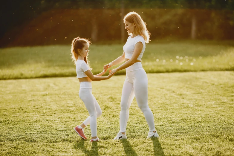 two women in white clothes holding hands on top of a green field