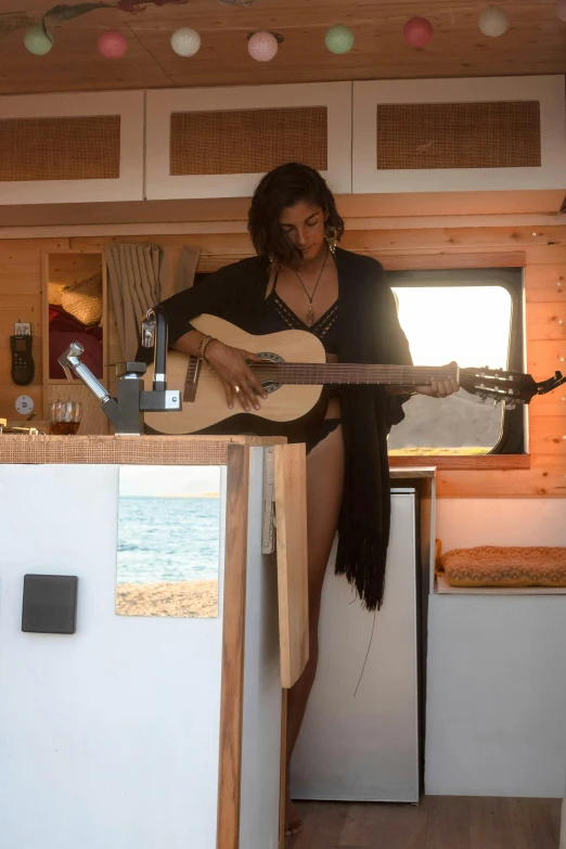 a woman in a tiny house with a guitar