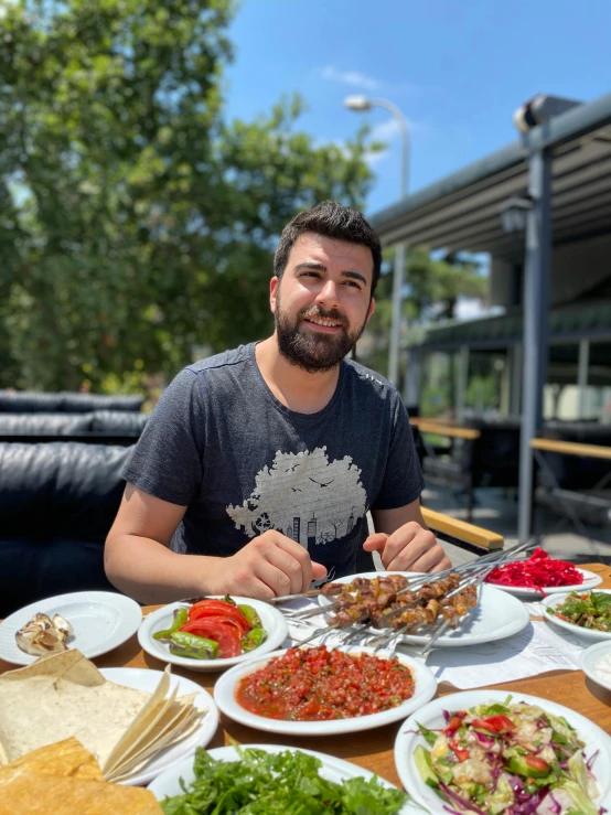 a man sitting at a table with plates of food in front of him