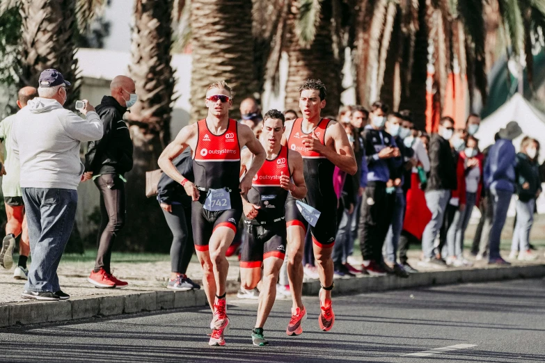 several marathon runners make their way down the road in front of spectators