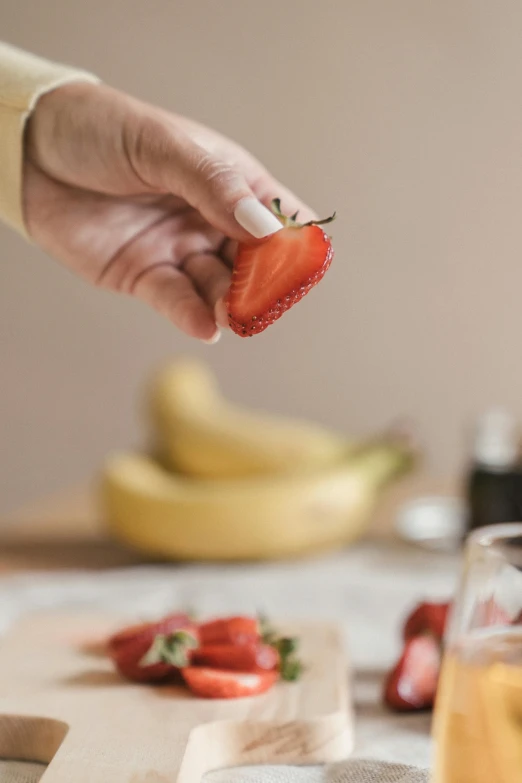 a person is holding up a piece of strawberries in front of some fruit