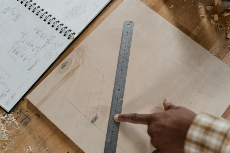 a man points to the ruler next to his work