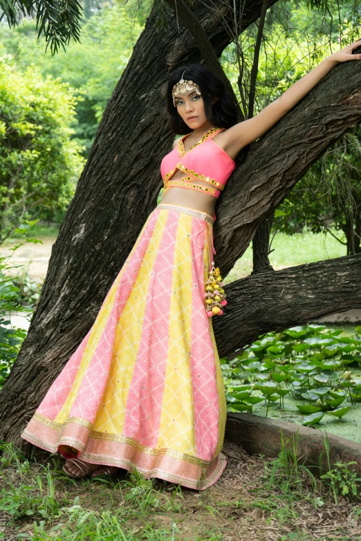 an asian woman poses leaning against a tree