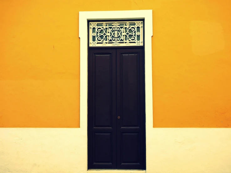 a white and black door is against a yellow wall