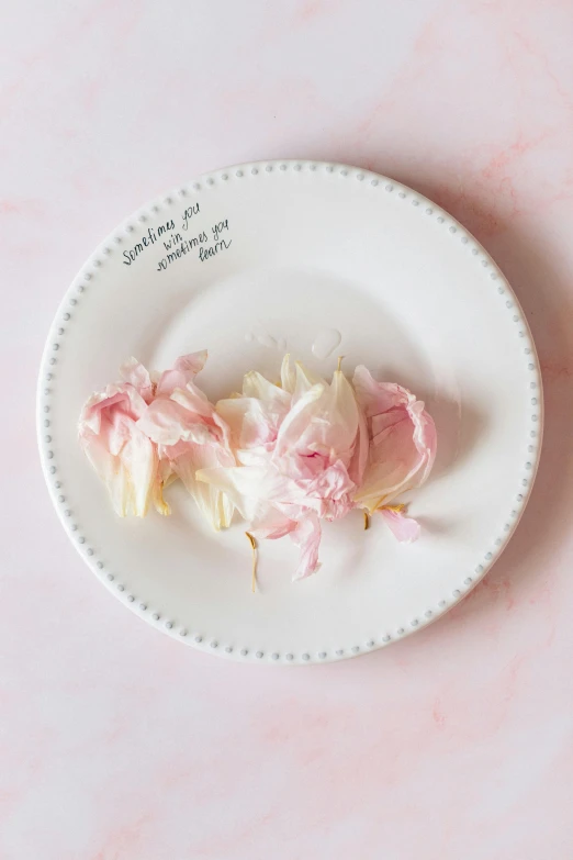 some flowers are on a plate on a pink table