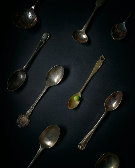 many spoons of various sizes on a black surface