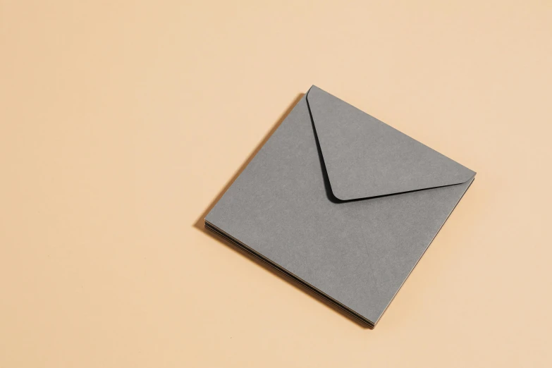 a grey envelope sitting next to a yellow wall