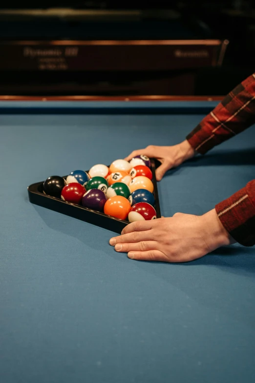 person holding game controller in pool table with lots of cues