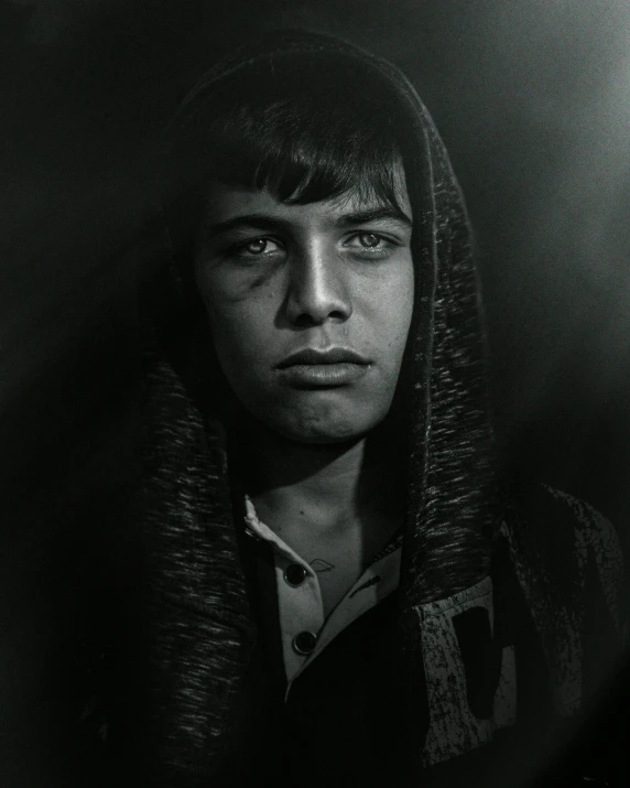 man with long hair and hoodie standing in dark background