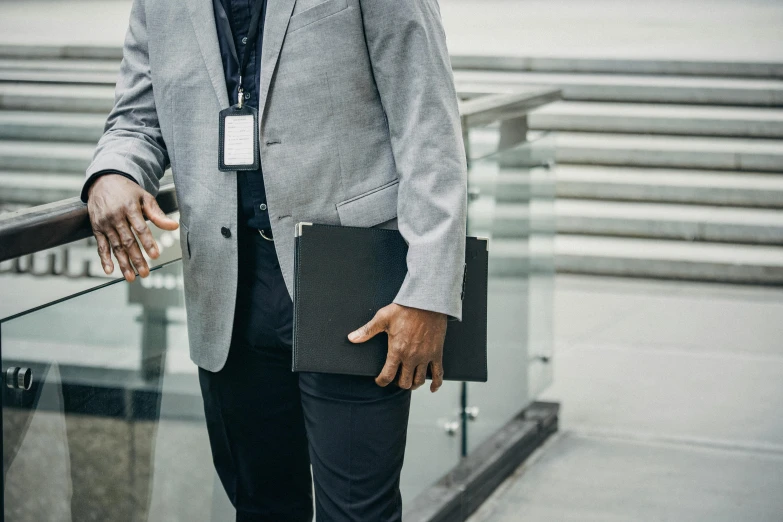 a man holding his suit and briefcase next to a railing