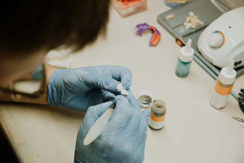 a person with blue gloves on holding medicine in his hand