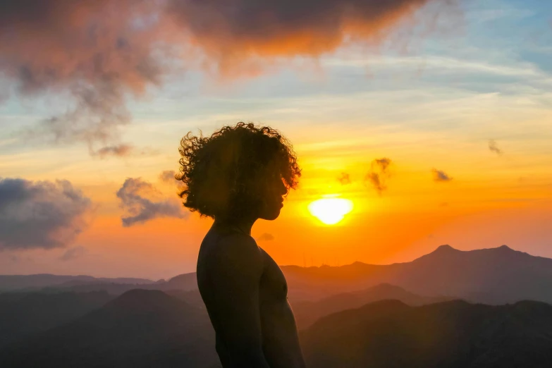 a young man with short hair staring at the sunset