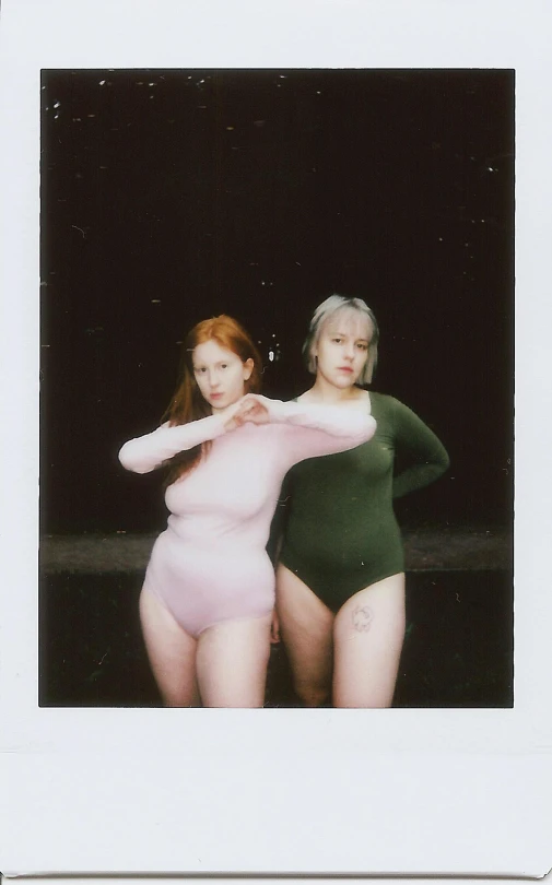 two young women in bathingsuits standing in a barn