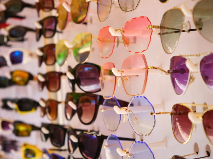 multiple colored sunglasses are displayed in a wall