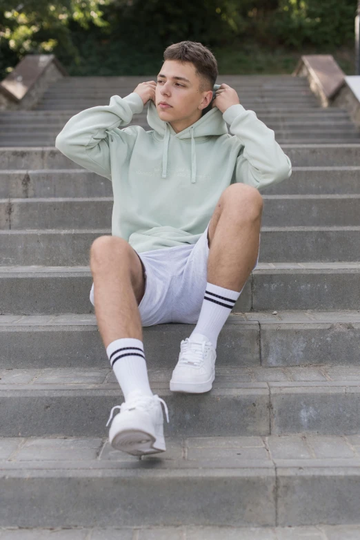 a young man sitting on steps, his hands in his ears