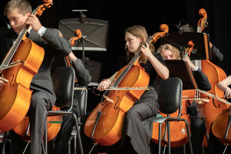 a man with a cellphone is sitting in front of the cello