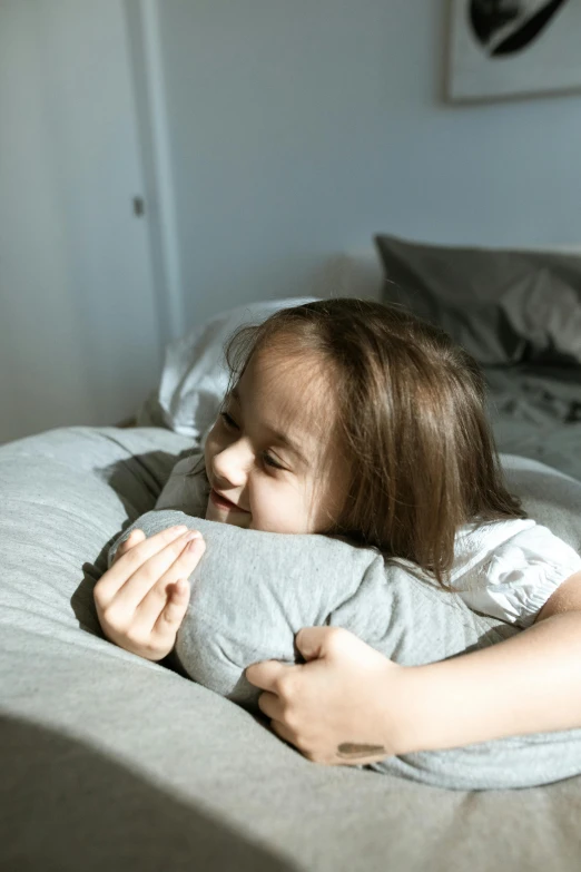 a  holding a stuffed animal on top of a bed