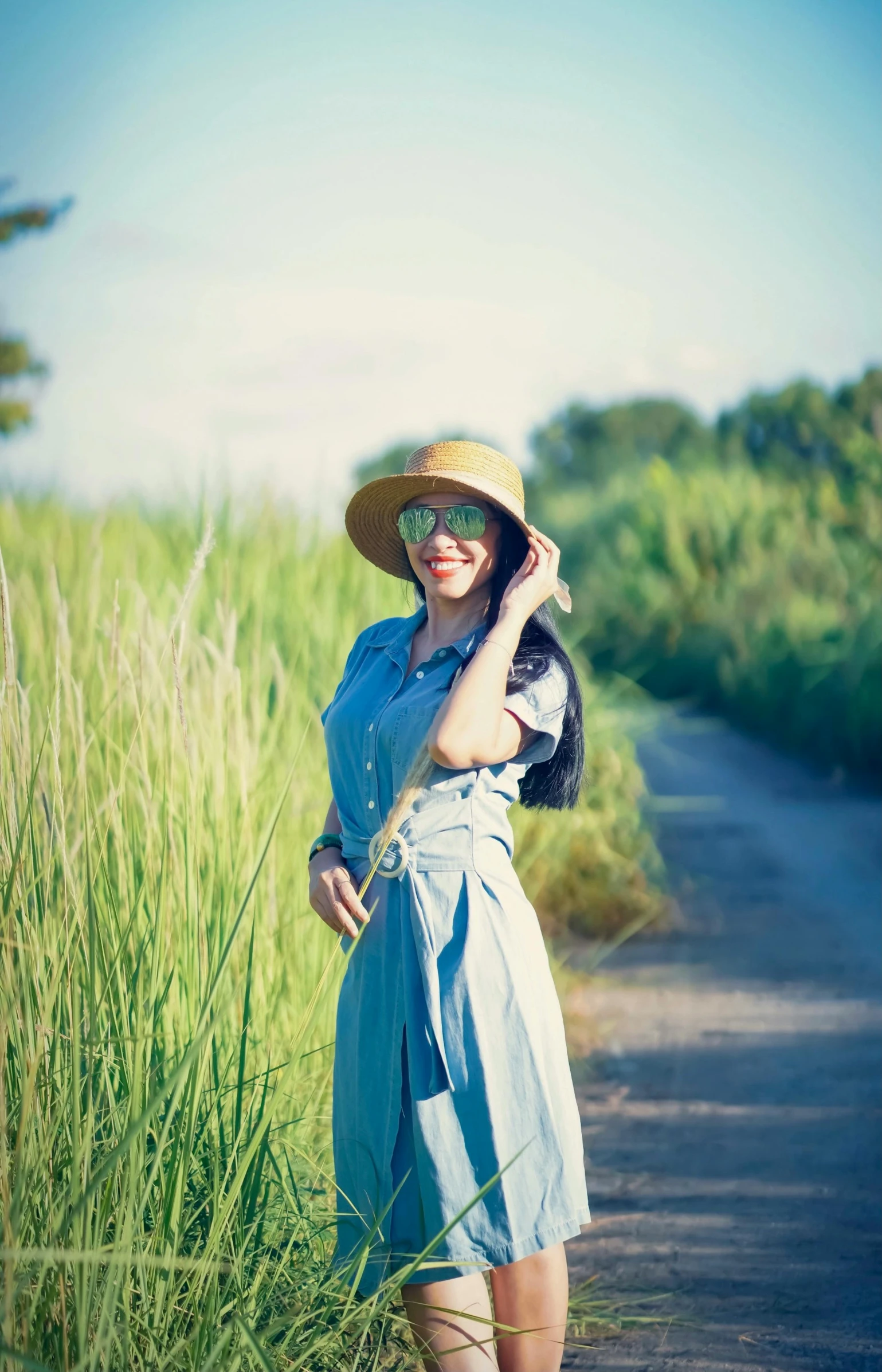 a woman in a sunhat poses while holding onto a cat