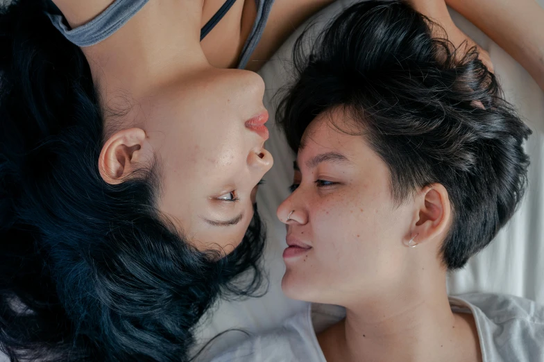 two young women lie next to each other in a bedroom