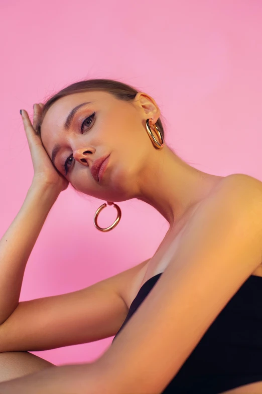 a young woman sitting with her eyes closed in the middle of her body wearing hoop earrings