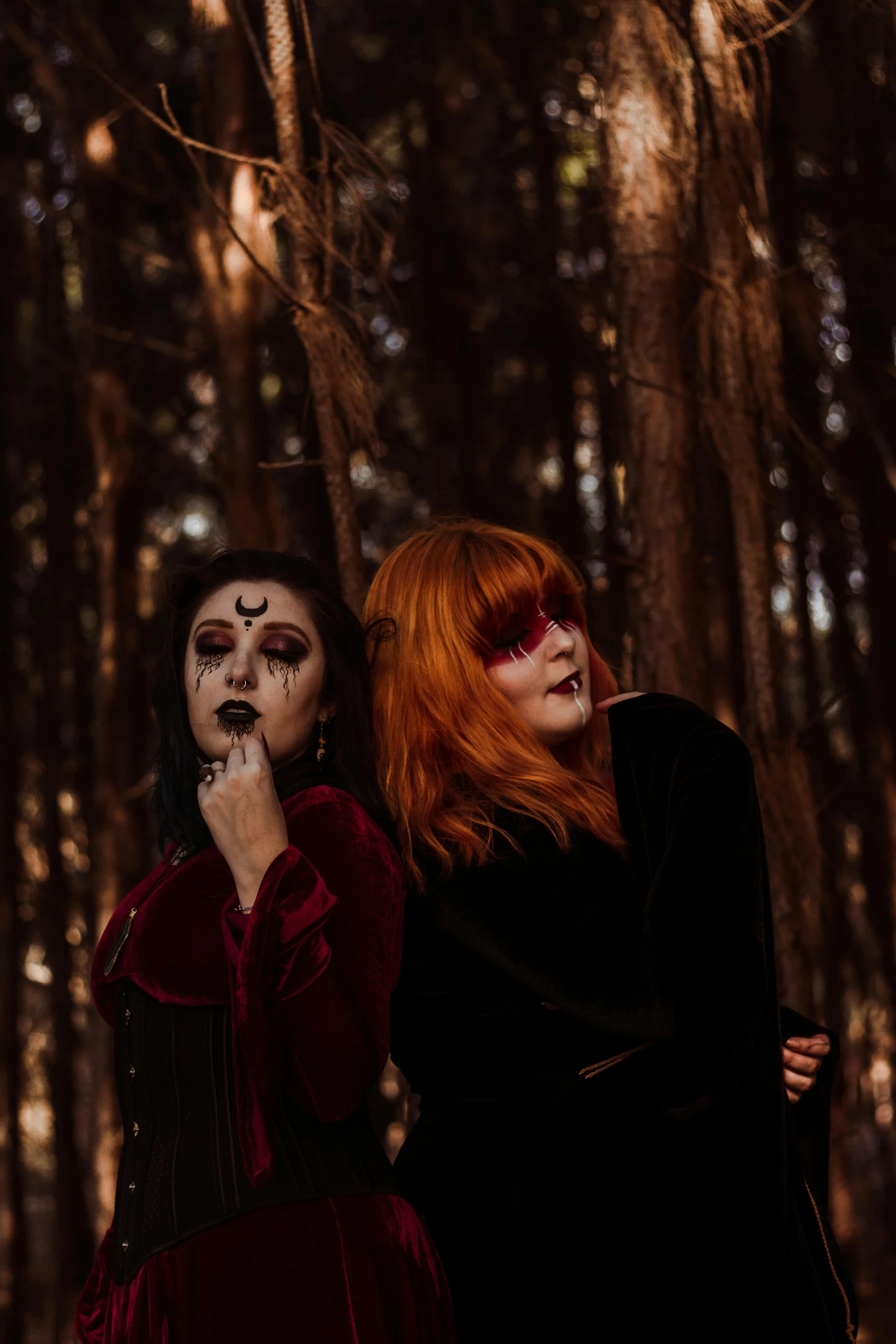 two red haired women with faces painted like cats in the woods