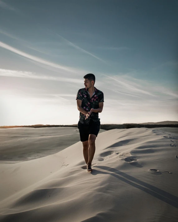 man walking in the sand at sunset on the beach