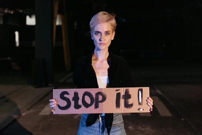 a woman holding up a sign that says stop it