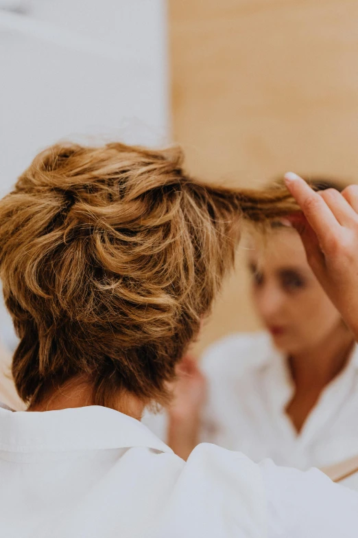 a woman who is using a hair dryer on her long blond hair