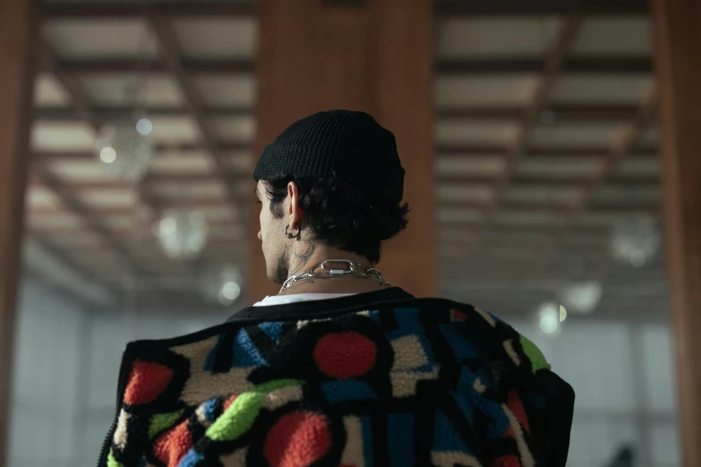 the back of a man's head with multiple patches on his sweater