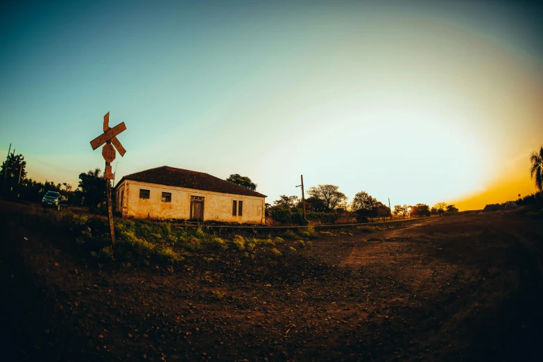 an abandoned white building is in the foreground and a railroad crossing sign, in the foreground