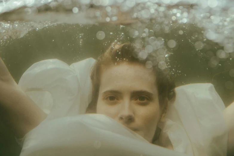 woman in white dress under water and holding a white sheet